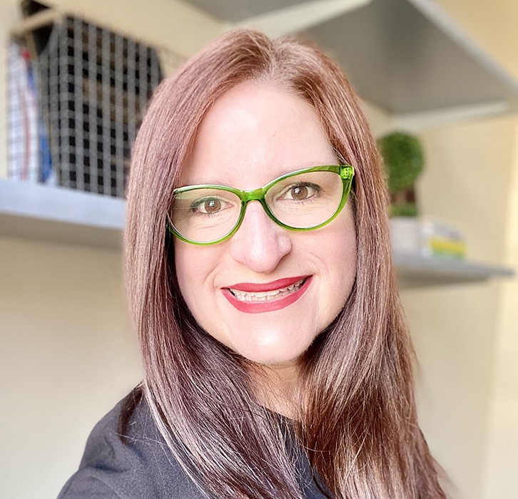Headshot of Dr. Bou, showing her light brown hair and lime green glasses.