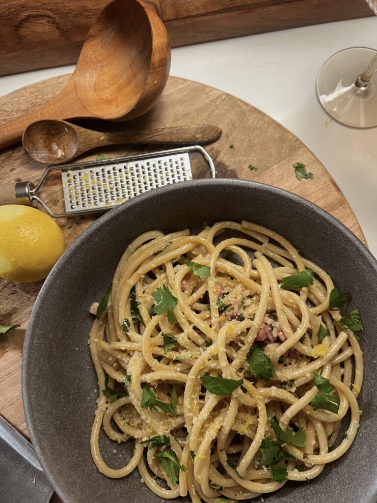 Spaghetti in a grey bowl with a lemon cream sauce and topped with parsley.