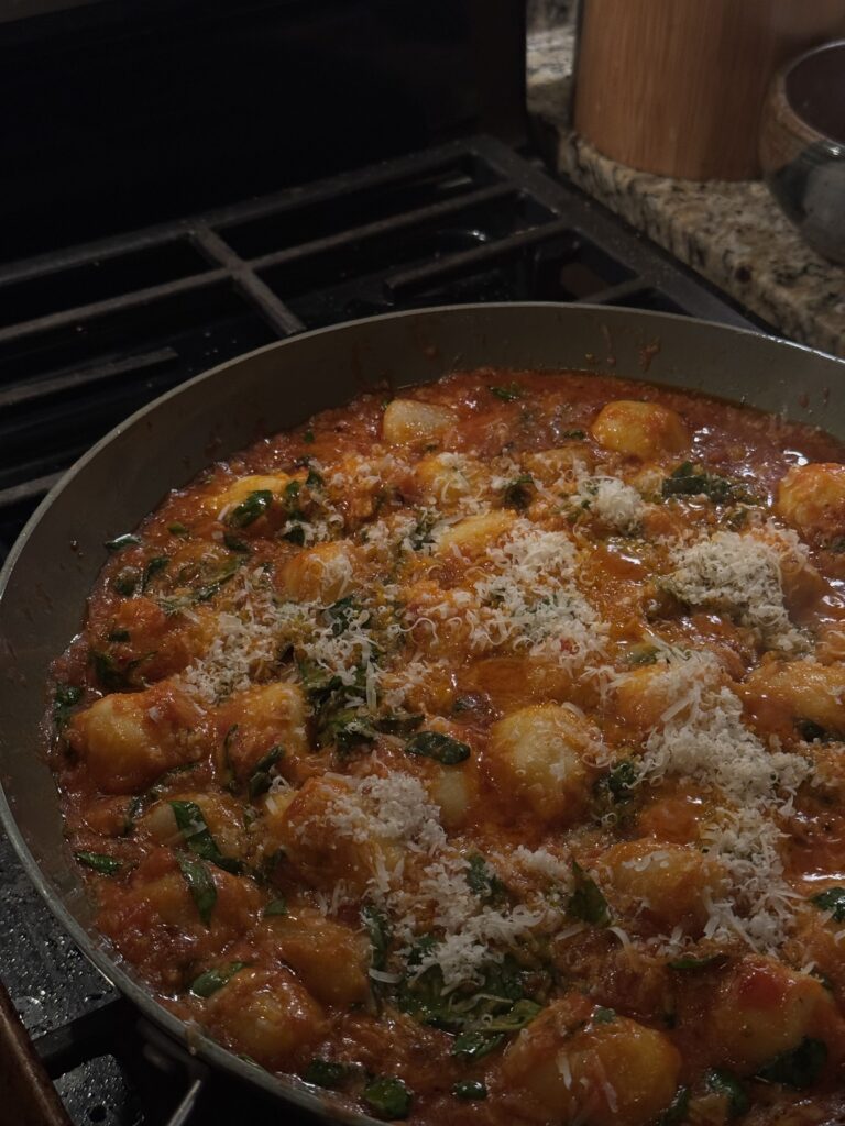 Gnocchi in a red sauce topped with parmesan cheese in a pan.