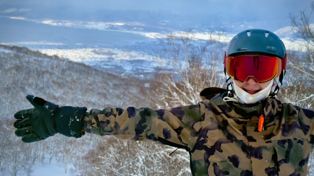 Leah stands at the time of a moment in snow gear with her arms outstretched.