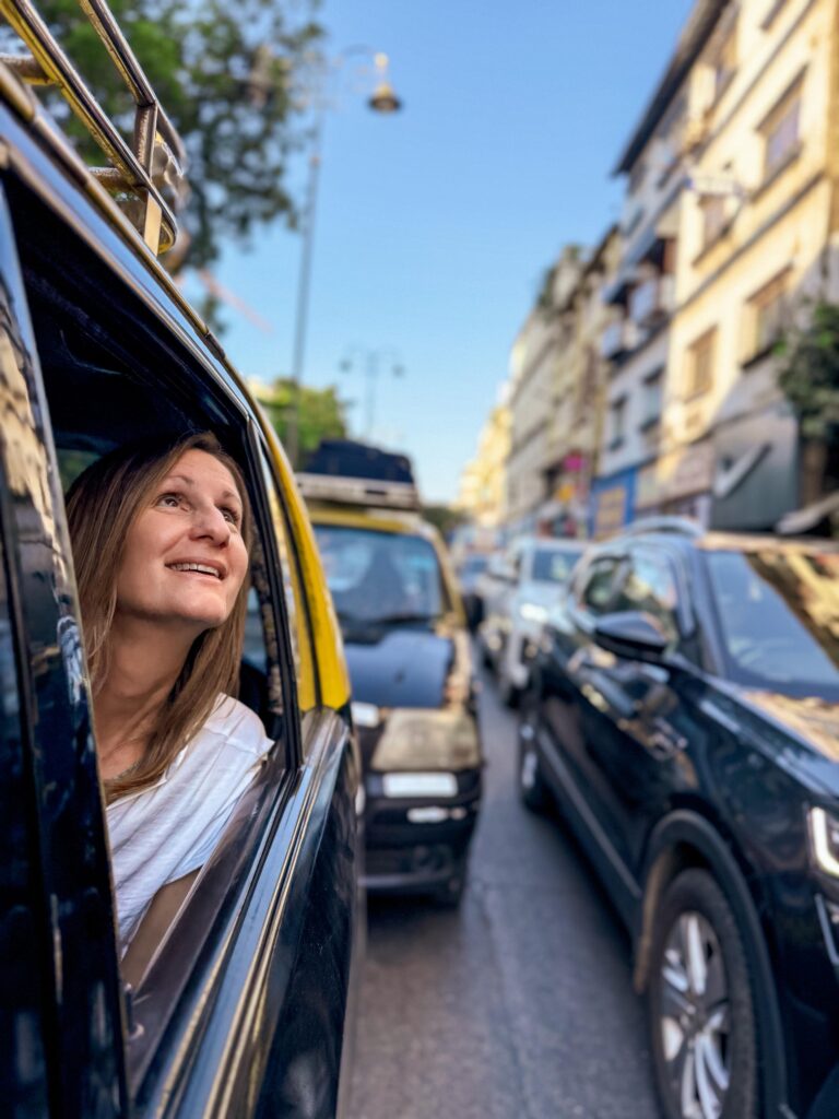 Leah gazes out a car window on a bustling city street.
