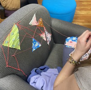 Student sewing fabric scraps onto a chair