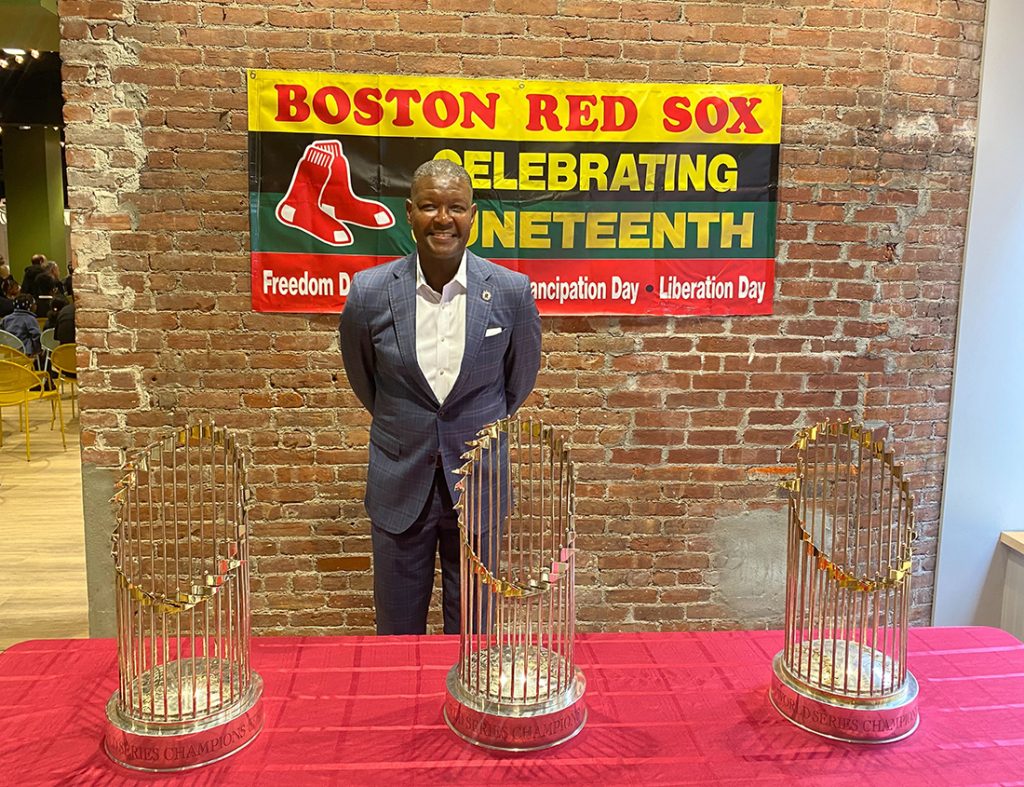 Stan Nance stands behind a table with three Red Sox World Series trophies