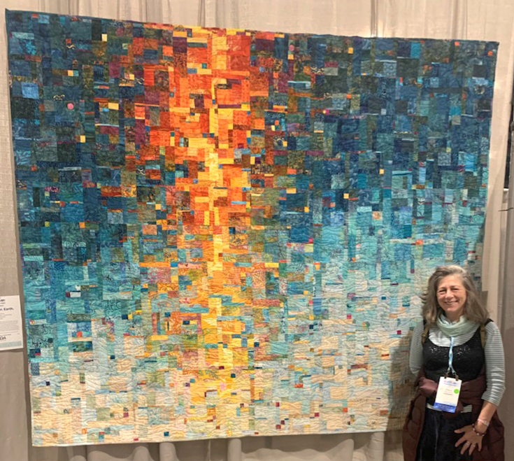 Diane Paxton stands in front of a quilt that she created.