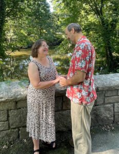 Estelle Ticktin and Steve Bohrer stand on a stone bridge and hold hands, recently married